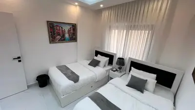 a white bedroom with two beds and a window at شقة مفروشة ثلاث غرف الجاردنز in Amman