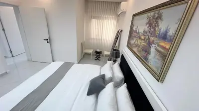 a white bedroom with a painting on the wall at شقة مفروشة ثلاث غرف الجاردنز in Amman