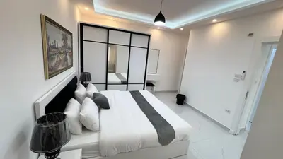 a bedroom with a white bed and a mirror at شقة مفروشة ثلاث غرف الجاردنز in Amman