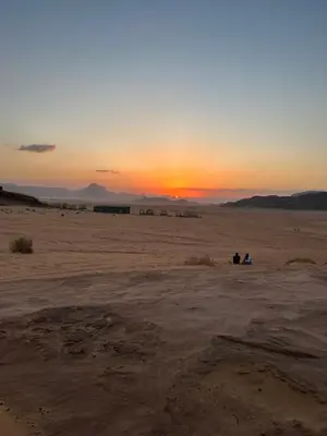 two people sitting in the desert watching the sunset at Lamis Camp Wadi Rum in Aqaba
