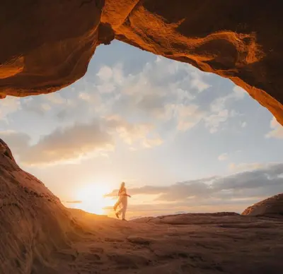 a person walking through a cave at sunset at Stars Night Camp in Wadi Rum