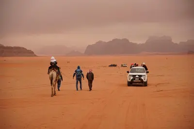 a group of people and a horse walking in the desert at Dune Camp Tours in Wadi Rum