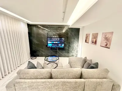 a living room with a couch and a flat screen tv at Brand New Stylish Luxe Apartment Near US Embassy Abdoun in Amman