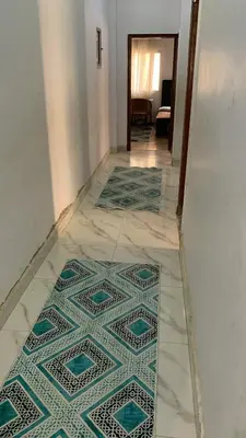 a hallway with a tile floor with two rugs at Family house in Petra