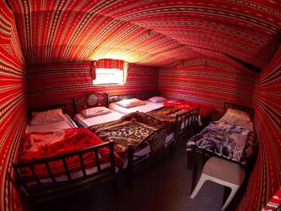 a room with four beds in a red room at Martian Desert Camp in Wadi Rum