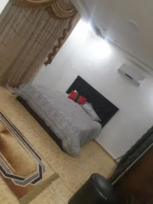 a bedroom with a bed with a gray comforter and a pillow at مزرعه الخال in Al Kafrayn