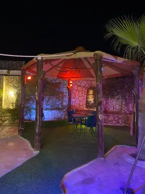 a gazebo with a table under it at night at مزرعه الخال in Al Kafrayn