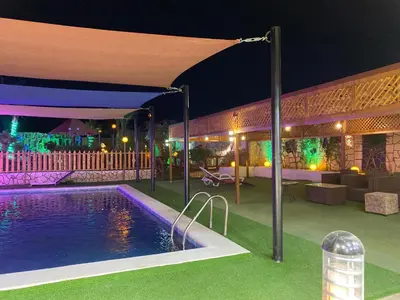 a swimming pool in front of a building at night at مزرعه الخال in Al Kafrayn