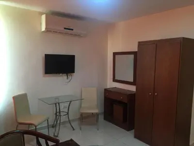 a room with a table and a cabinet and a television at Zaina Plaza Hotel in Amman