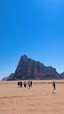 a group of people walking on a beach in the desert at Jawad wady rum in Disah