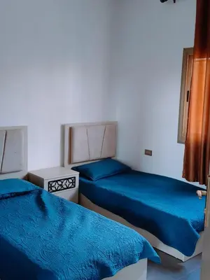 two beds in a room with blue sheets at شاليه كل الفصول in Dawqarah