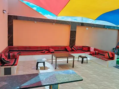 a room with red couches and tables and an umbrella at شاليه كل الفصول in Dawqarah