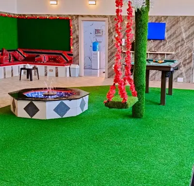 a room with a green floor with a fountain and a table at شاليه كل الفصول in Dawqarah