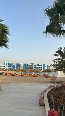 a beach with some umbrellas and a building at One bedroom at ayla azure in Aqaba