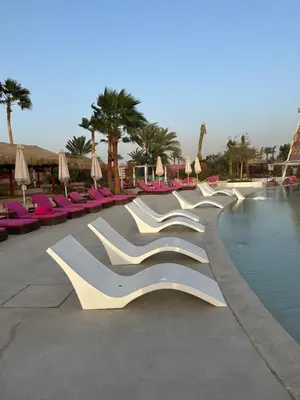 a row of white chairs next to a swimming pool at One bedroom at ayla azure in Aqaba