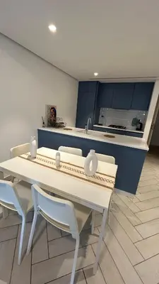 a kitchen with a white table and white chairs at One bedroom at ayla azure in Aqaba