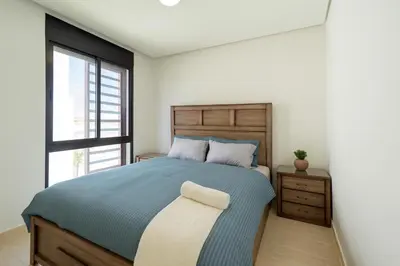 a bedroom with a blue bed and a window at Ayla Oasis Golf Apartment - Ayla Vista in Aqaba