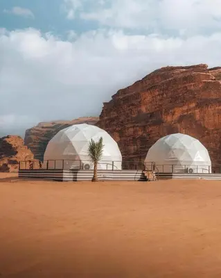 two domes in the desert near a rock formation at وادي رم مخيم in Wadi Rum