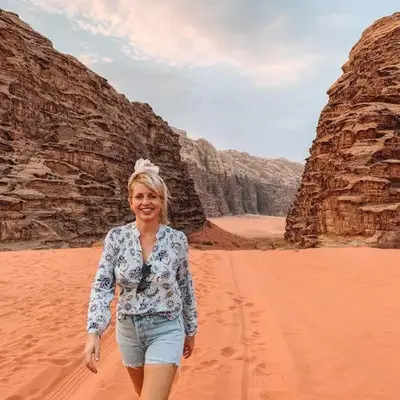 a woman standing in the desert near some rocks at وادي رم مخيم in Wadi Rum