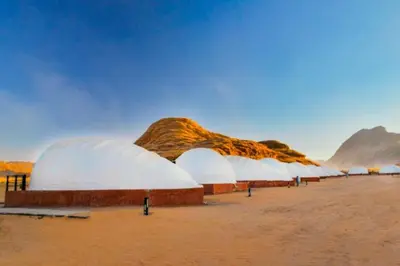 a row of domes in the desert with mountains in the background at Luxury Spiral Camp in Maḩaţţat Dīsah