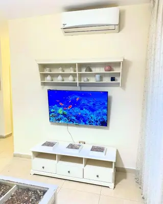 a living room with a tv on a wall at Abdoun Modern 2BR Apartment Near US Embassy in Amman