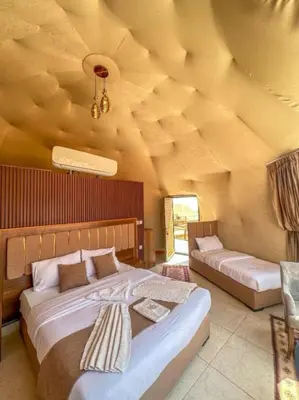 a bedroom with two beds in a room with a wooden ceiling at RUM iSLAND bubble LUXURU CAMP in Wadi Rum