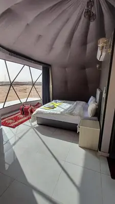 a bed in a room with a large window at RUM iSLAND bubble LUXURU CAMP in Wadi Rum