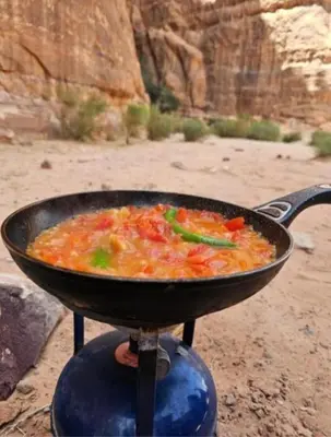 a pan of food is cooking on a stove at RUM iSLAND bubble LUXURU CAMP in Wadi Rum