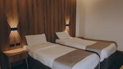 a hotel room with two beds and two lights at Sandy Palace Hotel Amman in Amman