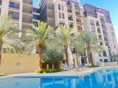 a swimming pool with palm trees in front of a building at شقه بغرفة نوم في قريه الراحة one bedroom apartment in alraha village in Al Jafr