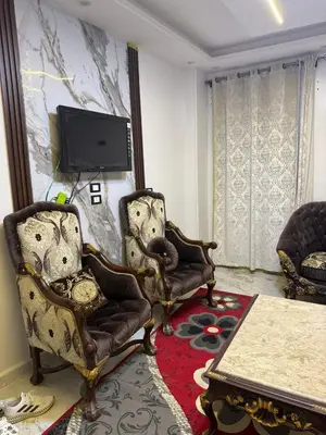 a living room with two chairs and a tv at Marco inn in Amman