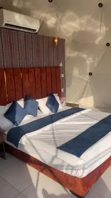 a bedroom with a large bed with blue pillows at Desert Horizon Camp in Disah