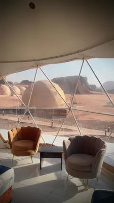two chairs and a table in a room with a large window at Desert Horizon Camp in Disah