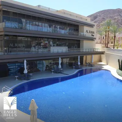 a hotel with a large swimming pool in front of a building at قرية الراحة مرسى زايد باطلالات خلابة alraha village with Beautiful view in Aqaba