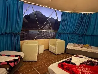 a room with two beds and a couch and a window at Wadi rum sami camp in Wadi Rum