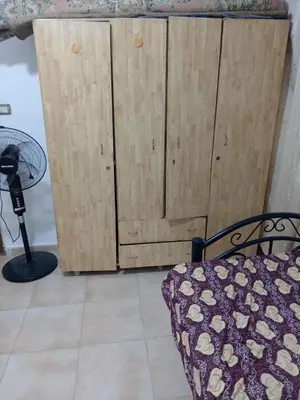 a bedroom with a wooden cabinet and a bed at Al Martini Building Number 11 in Amman