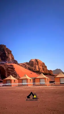 a building in the desert with mountains in the background at millennium camp in Wadi Rum