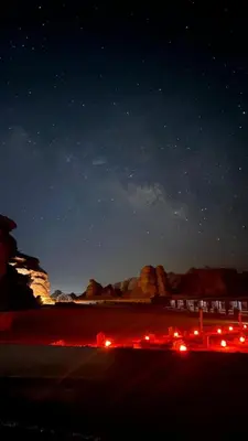 a night time view of a beach with a starry sky at Wadi Rum Aura Camp in Wadi Rum