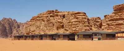 a building in the desert next to a mountain at Wadi Rum Aura Camp in Wadi Rum