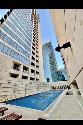 a large building with a swimming pool in front of it at Pasha House - DAMAC Tower in Amman
