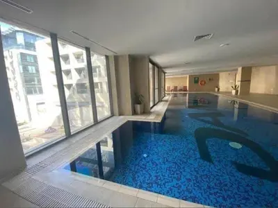 a large swimming pool in a building with a large window at Pasha House - DAMAC Tower in Amman