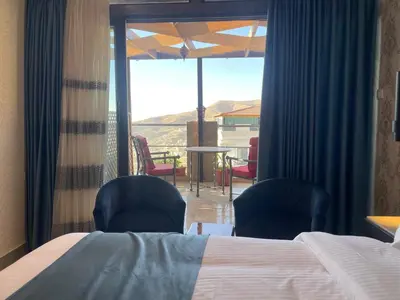 a bedroom with a bed and two chairs and a balcony at Petra night hostel in Wadi Musa