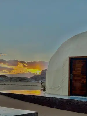 a tent on the beach with a sunset in the background at Bedouin Luxe Camp & Tour in Wadi Rum
