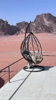 a bird cage sitting on a ledge near the desert at Bedouin Luxe Camp & Tour in Wadi Rum