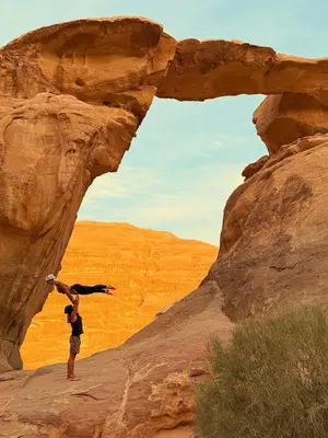 a person climbing on a rock formation in the desert at Sunrise Magic Camp in Wadi Rum