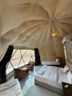 a bedroom with a tent with two beds and a chair at TALA lUXURY CAMP in Wadi Rum