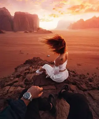 a man and woman sitting on a rock in the desert at Rum marea in Disah