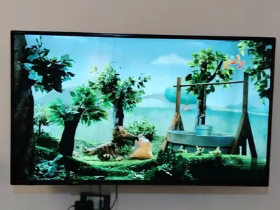 a television screen with a picture of a dog and trees at الرائد للشقق المفروشة in Amman