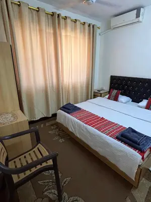a bedroom with a large bed and a chair at New Hamoudeh Hotel in Amman