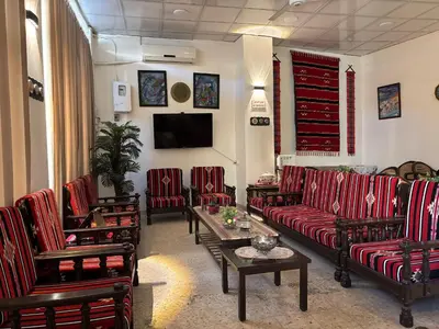a living room with couches and chairs and a tv at New Hamoudeh Hotel in Amman